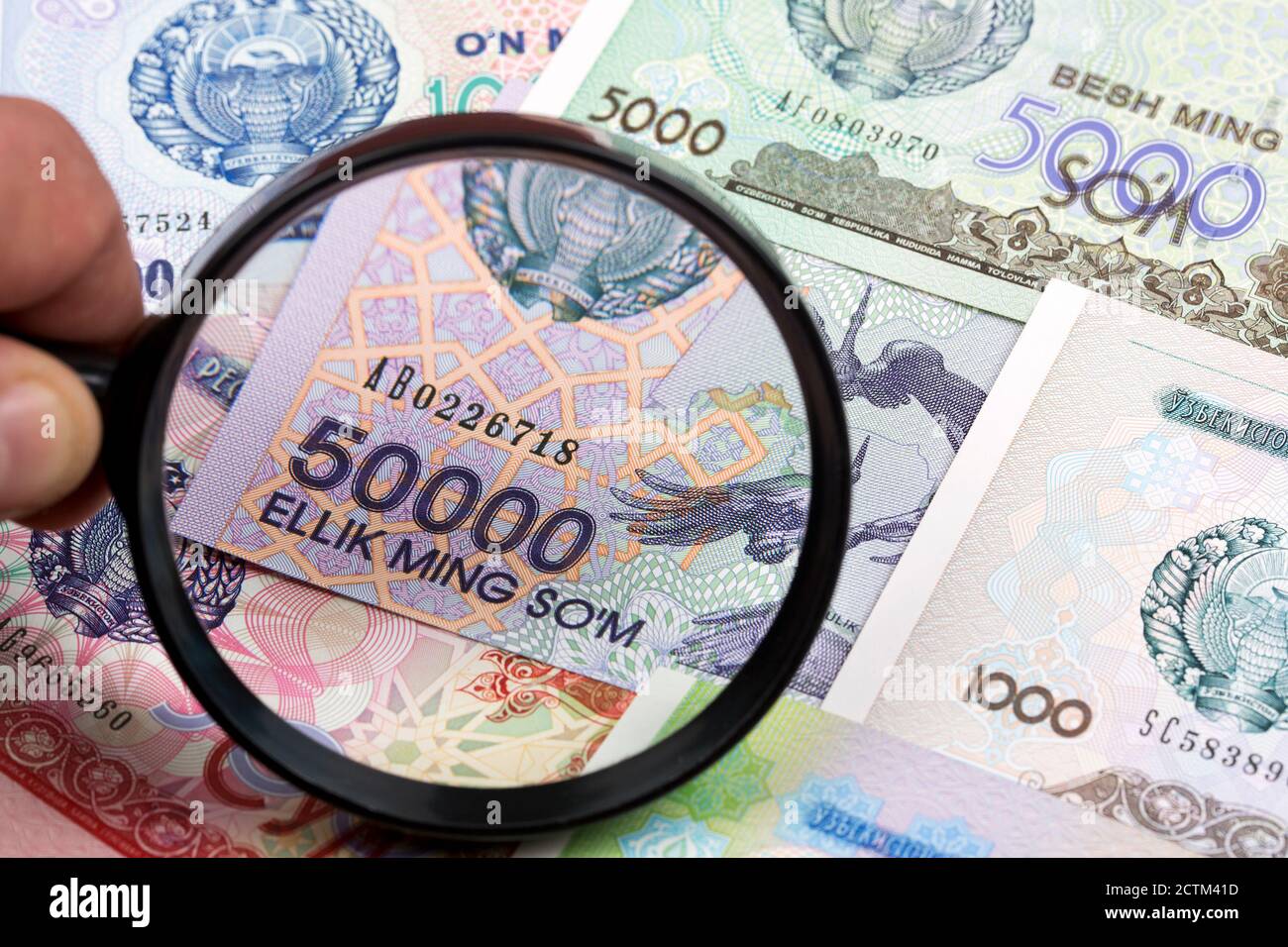 Usbekische Geld in einer Lupe ein geschäftlicher Hintergrund Stockfoto