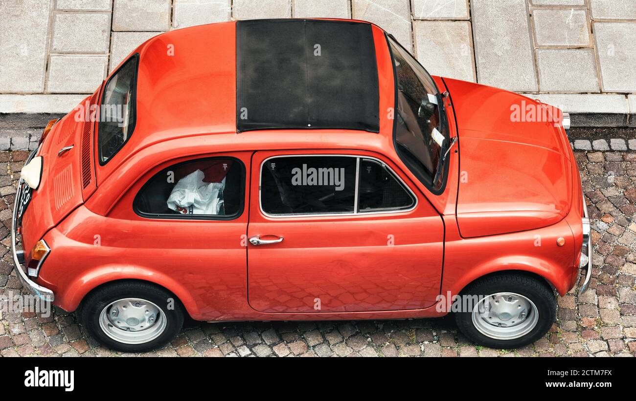Red Fiat 500 geparkt auf einer italienischen Kopfsteinpflasterstraße. Italienische Oldtimer. Stockfoto