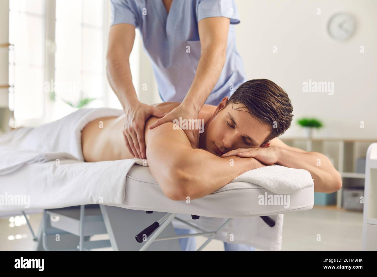 Entspannter junger Mann bekommt zurück Massage von professionellen Massagisten getan Oder Physiotherapeut Stockfoto
