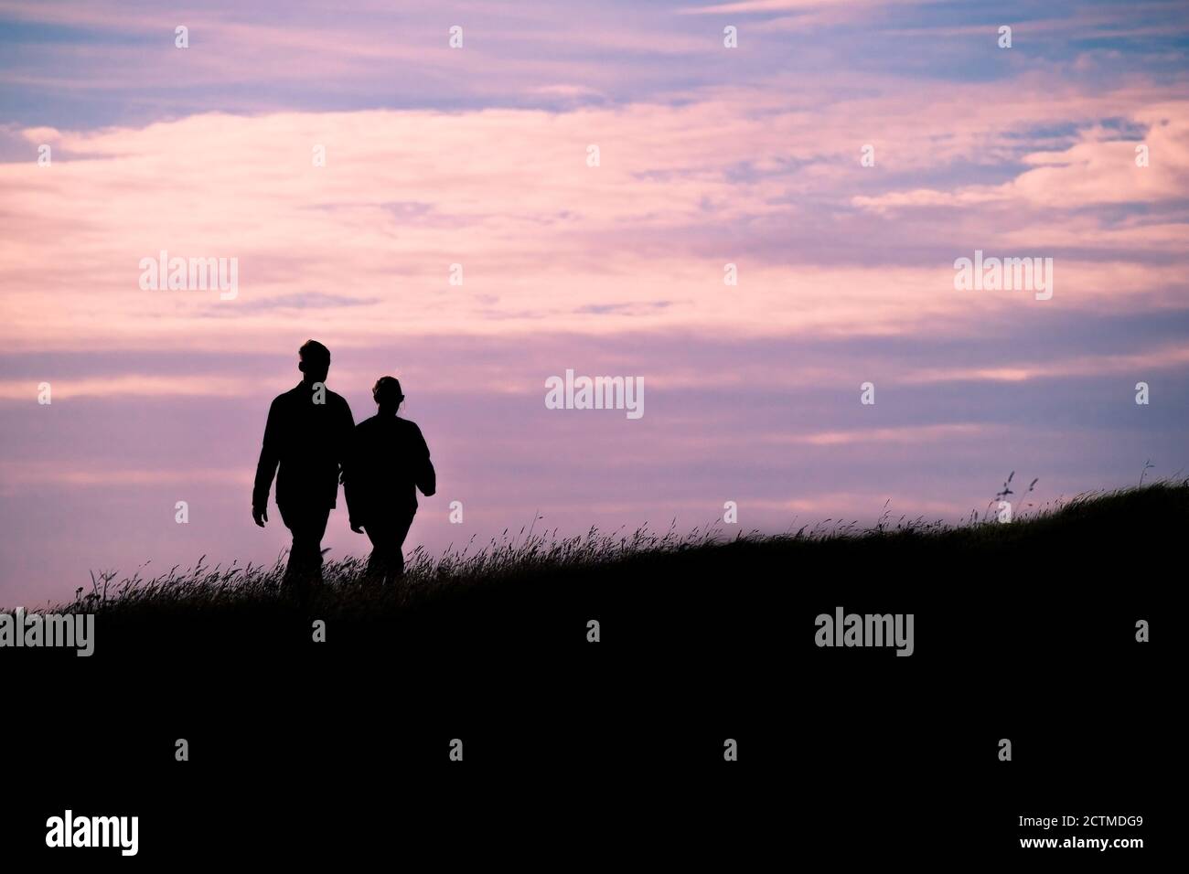 Zwei Spaziergänger, die durch die späte Abendsonne silhouetted werden. Stockfoto