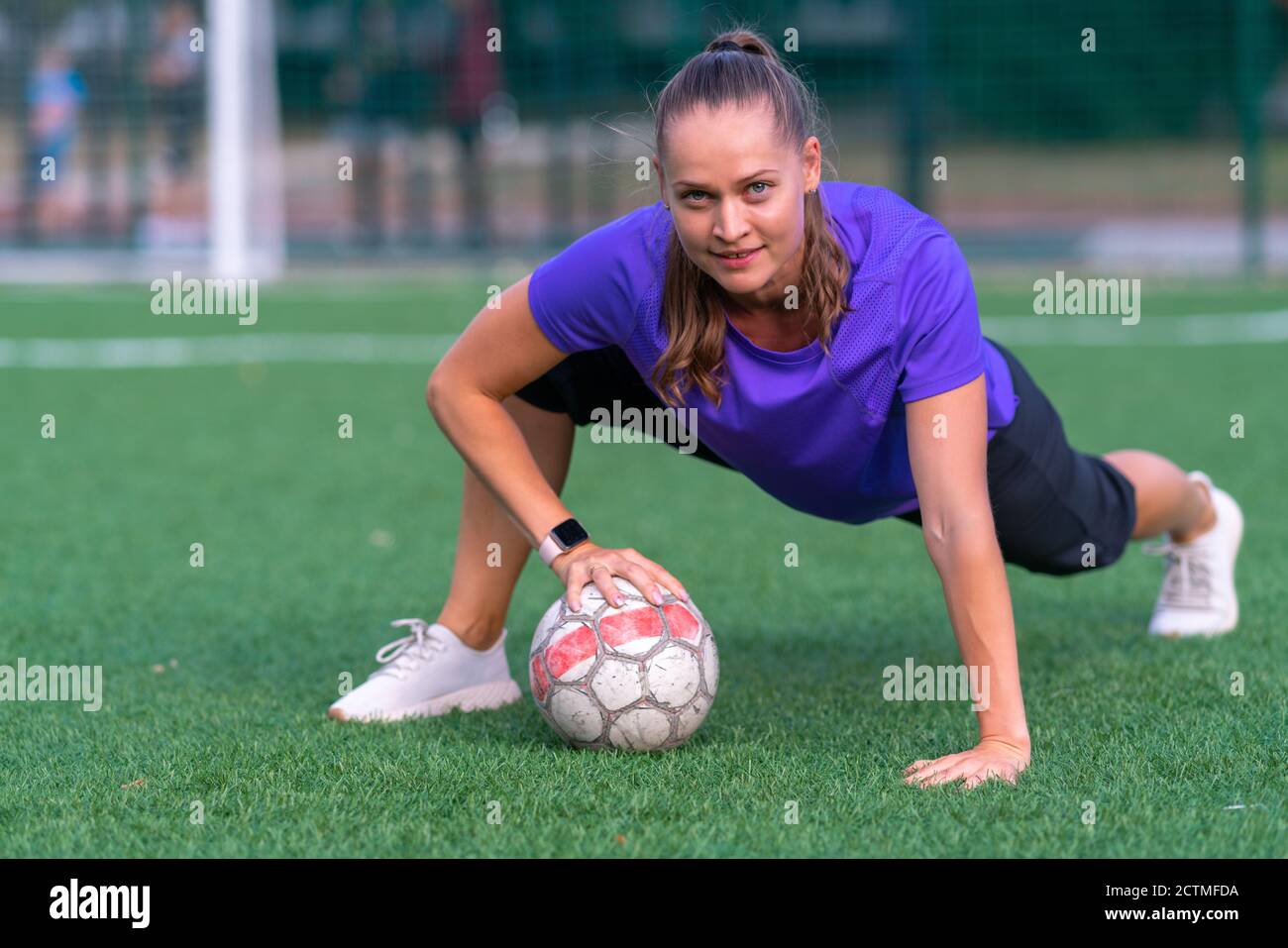 Fit gesunde junge Frau posiert mit Fußball auf einem Grüner Sportplatz in  ebener Ansicht von ihr Lächelnd auf die Kamera in einer Gesundheit und  Fitness oder Stockfotografie - Alamy