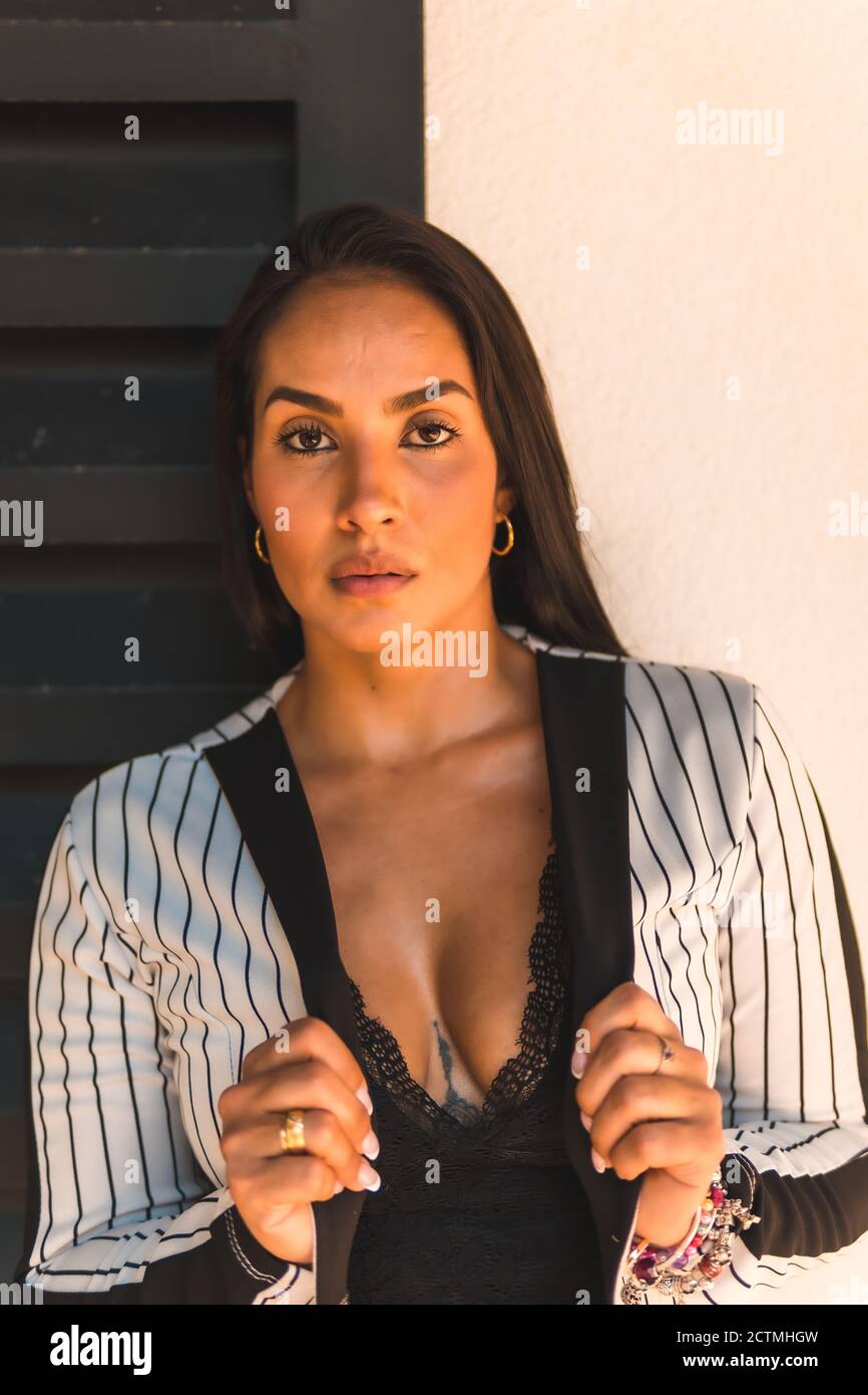 Attraktive geradhaarige Latein Brünette Mädchen in einem weißen Anzug mit Schwarze Streifen Stockfoto