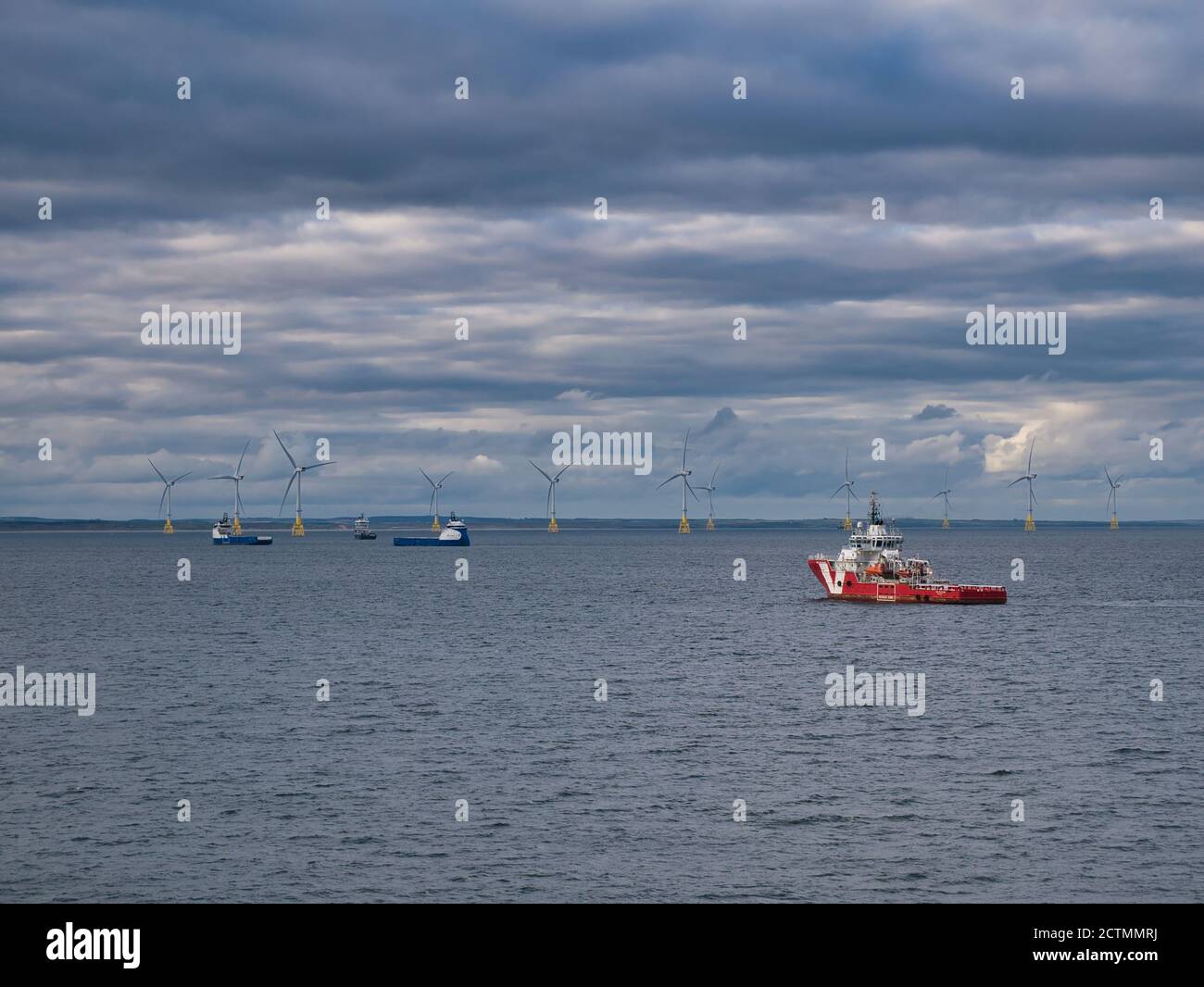 Windparkturbinen und Hilfsschiffe vor der Küste von Aberdeen in Schottland, Großbritannien, an einem ruhigen Tag mit bewölktem Himmel aufgenommen Stockfoto