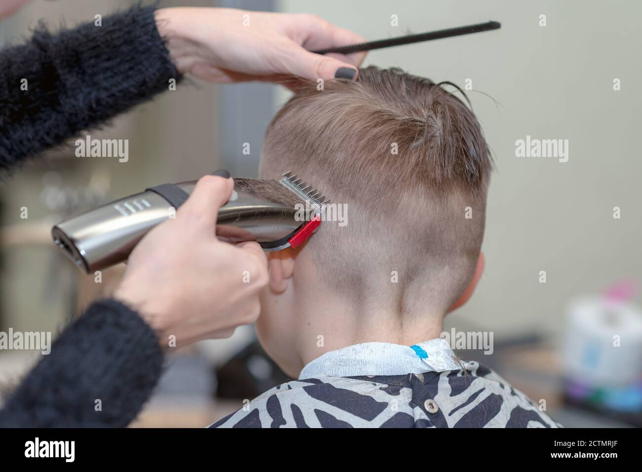 Rückansicht Happy boy sitzt im Friseursalon mit nassem Haar und schneidet ihr Haar. Stockfoto