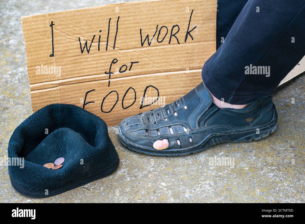 Arbeitslosigkeit Konzept Mann in alten zerrissenen Schuhen sitzt auf der Boden zu seinen Füßen Pappschild sagen, ich werde arbeiten Für Futter neben einer Kappe mit kleinen Almosen Coi Stockfoto