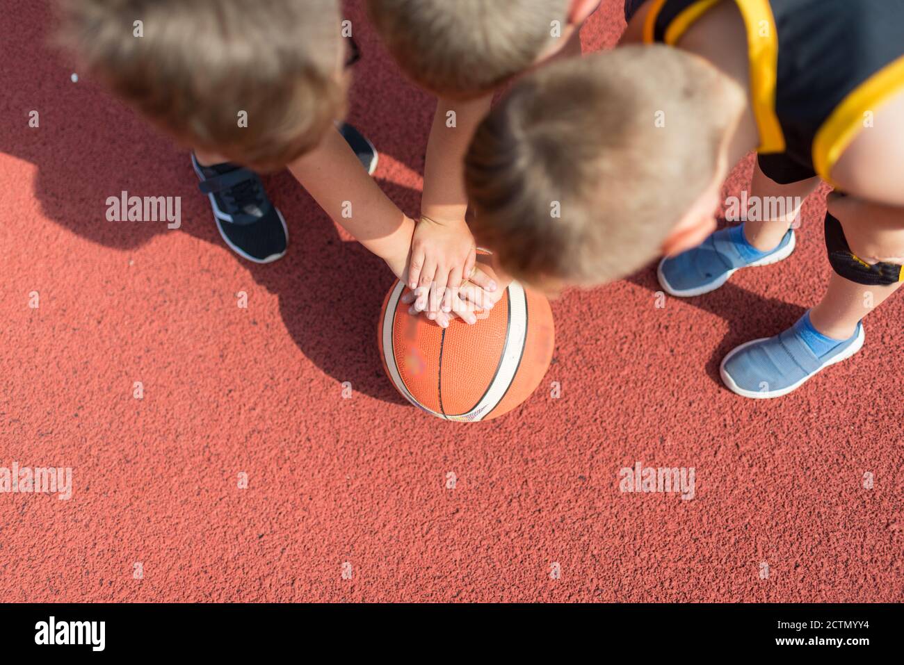 Draufsicht Kinder Basketball Team. Junge Basketballspieler berühren Bälle auf dem Basketballplatz. Basketball Horizontal rot Hintergrund. Stockfoto