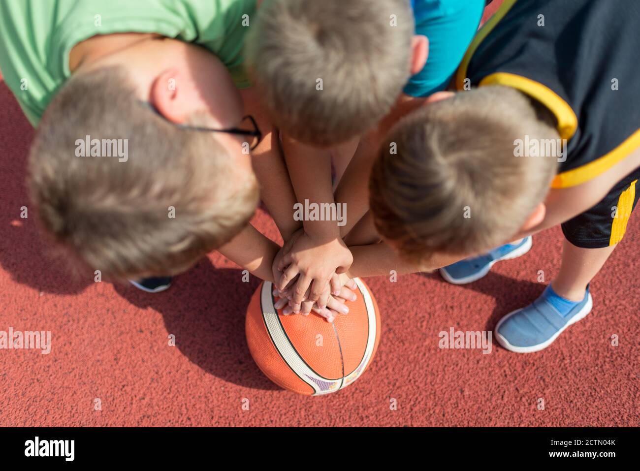 Draufsicht Kinder Basketball Team. Junge Basketballspieler berühren Bälle auf dem Basketballplatz. Basketball Horizontal rot Hintergrund. Stockfoto
