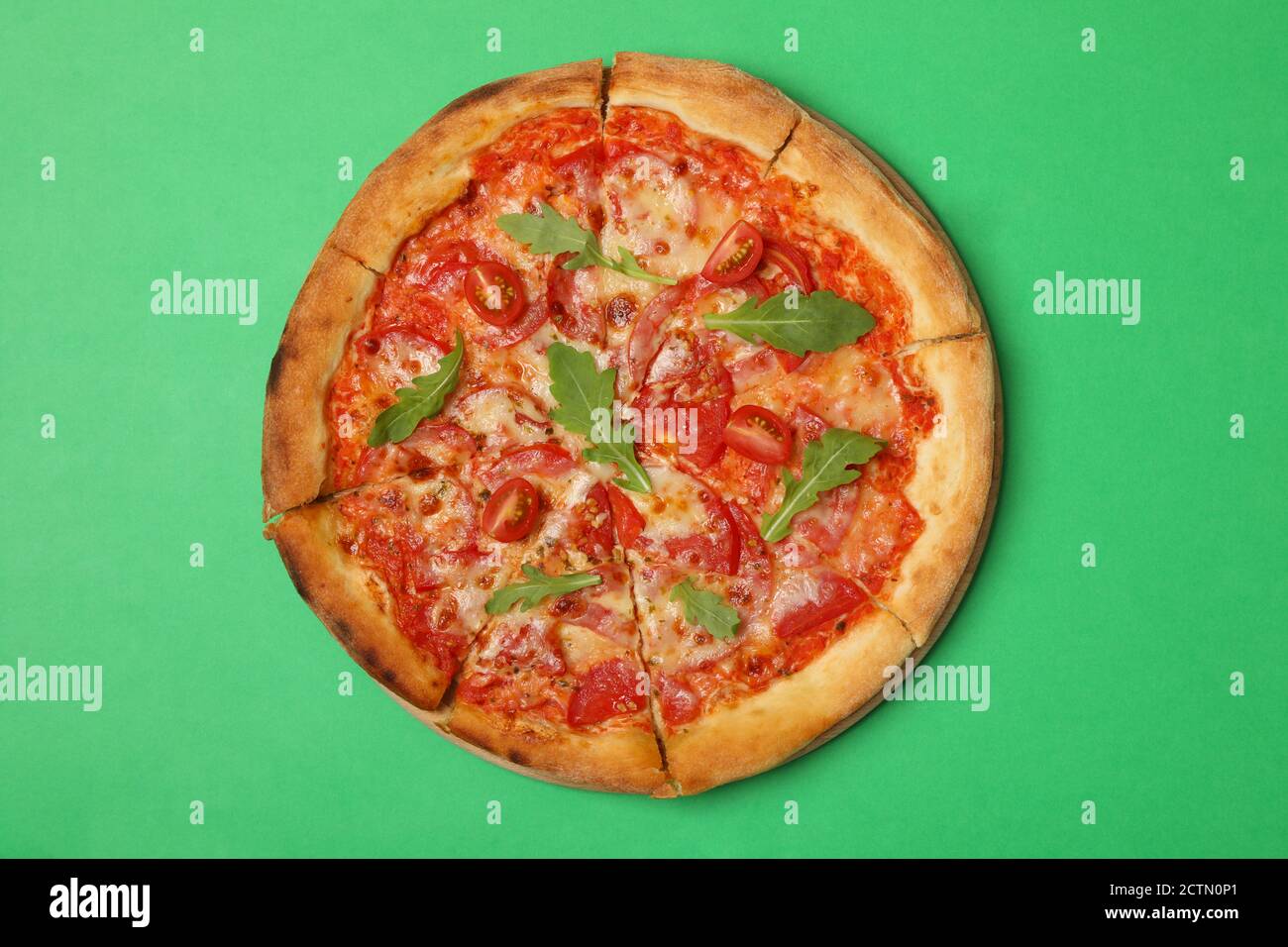 Leckere Pizza mit Tomate auf grünem Hintergrund Stockfoto