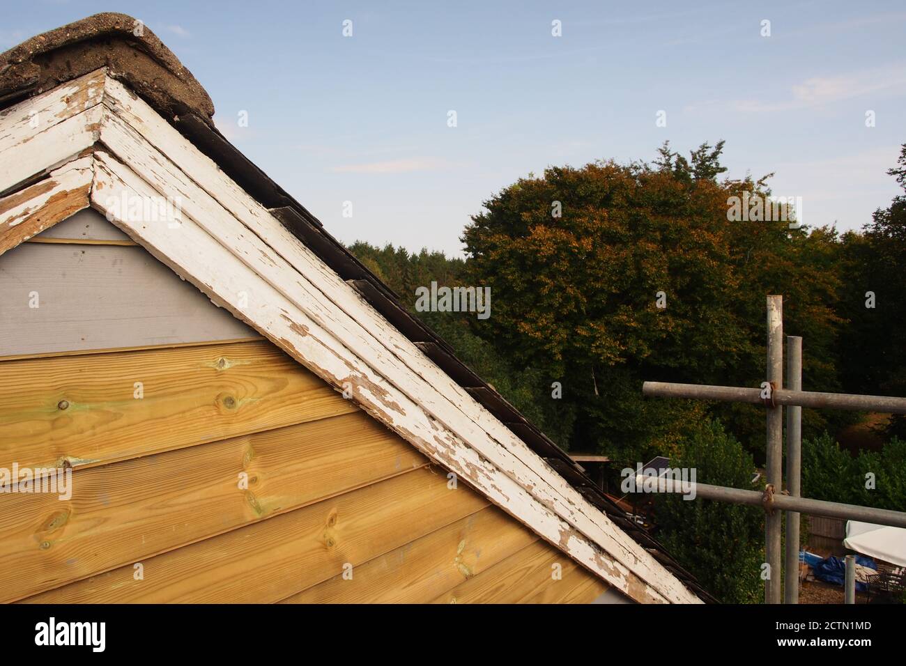Blick vom Gerüst auf das reparierte Giebelende eines alten Holzhauses mit Schieferdach, das noch lackiert werden muss, plus alte Lastkahn-Bretter Stockfoto