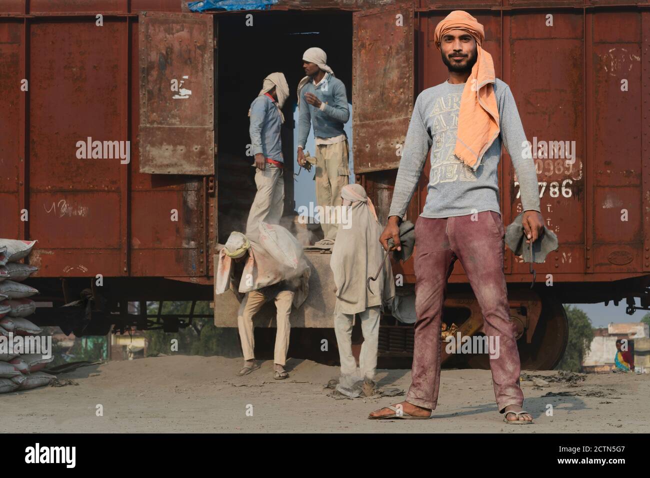 Porträt eines Mannes, der nur Kopftuch als Schutz trägt, der eingesetzt wird, um Zementsäcke vom Zug auf Lastwagen in Mathura, Uttar Pradesh, Indien, zu transportieren. Stockfoto