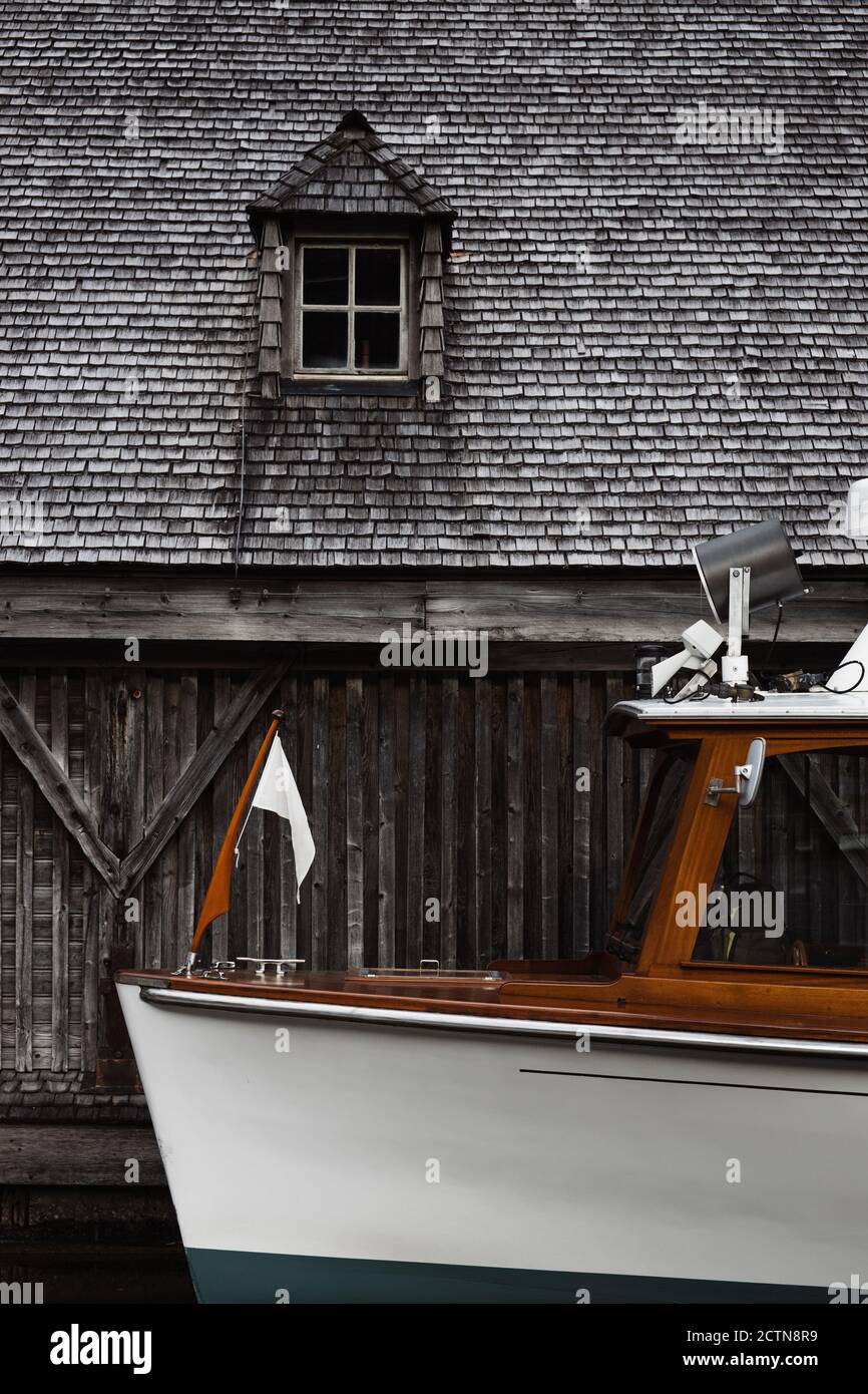 Moderne Motorschiff in der Nähe verwitterten grauen hölzernen Bootsschuppen vertäut Mit kleinem Fenster am Wasser Stockfoto
