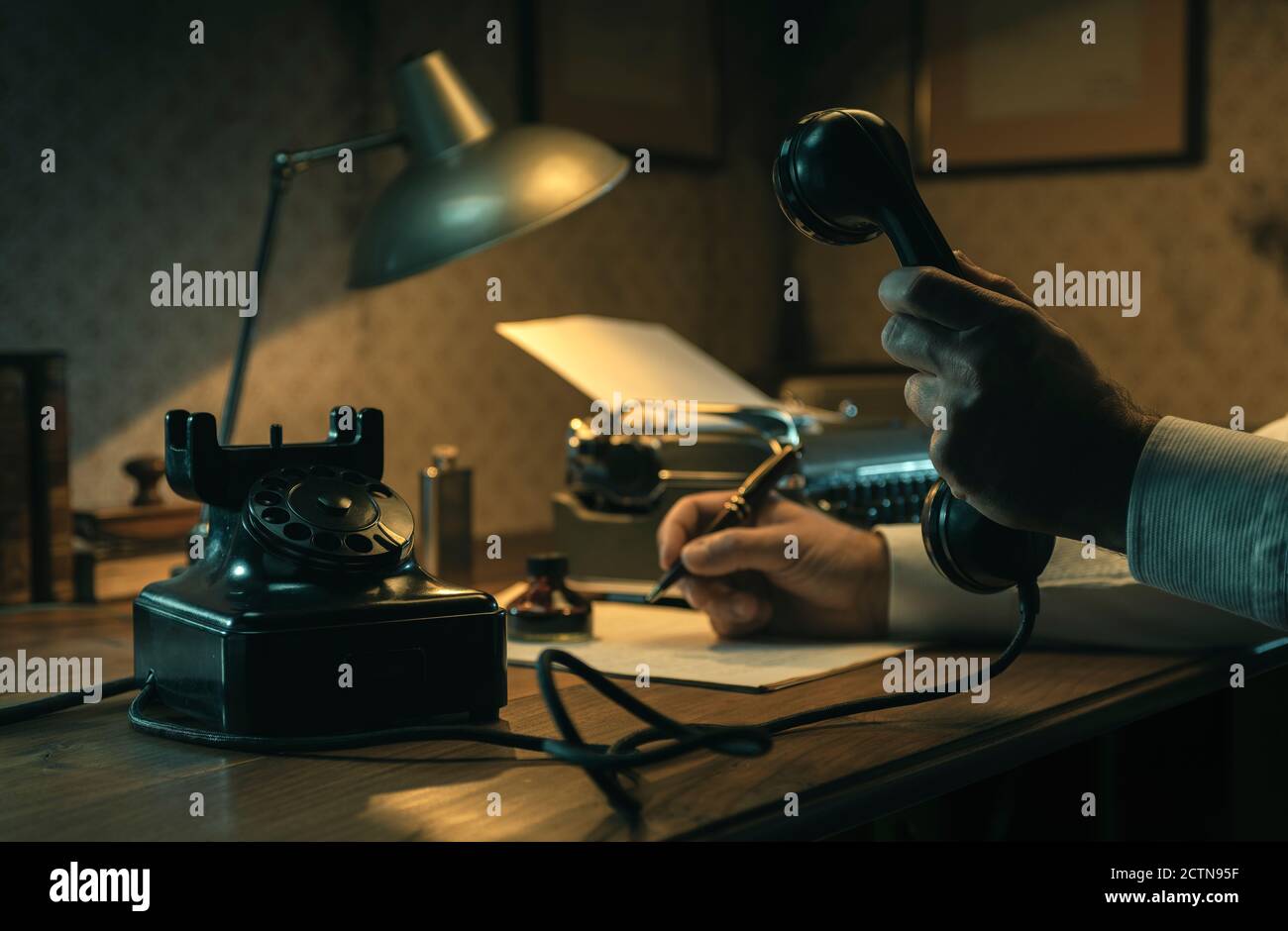Film noir Journalist arbeitet am Schreibtisch im Büro, hält er den Telefonhörer und schreibt Notizen Stockfoto