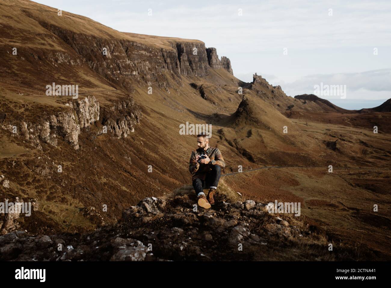 Männlicher Tourist mit professioneller Fotokamera, die Bilder nimmt und bewundert Wunderschöne Berge in den schottischen Highlands im Herbst Stockfoto