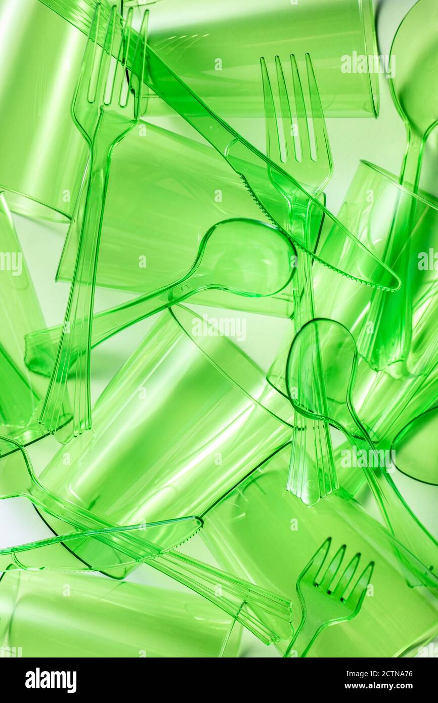 Draufsicht Zusammensetzung der leuchtend grünen transparenten Kunststoff Tassen mit Gabeln und Löffel und Messer auf weißem Hintergrund platziert Stockfoto