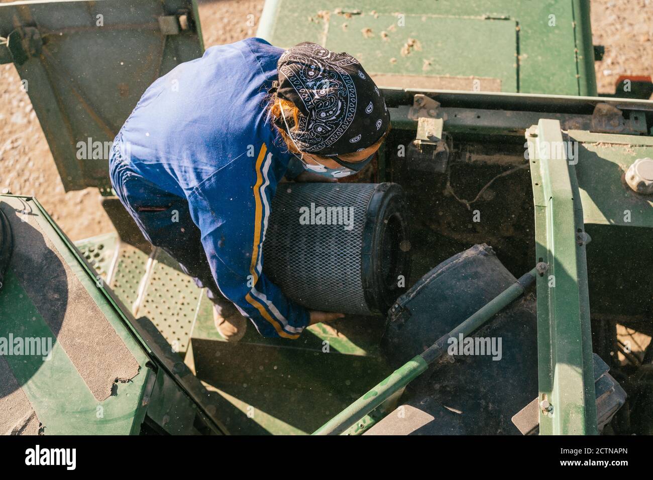 Von oben nicht erkennbaren Landwirt in Arbeitskleidung Reinigungsfilter der Landwirtschaft Kombinieren Sie Harvester in Hof Stockfoto