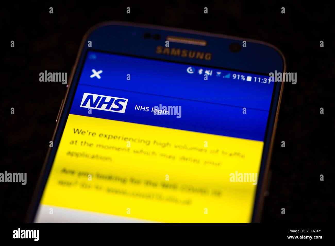 Die NHS Track and Trace App auf dem Bildschirm von Ein Android-Handy mit einer Nachricht, dass hohe Volumen Der Verkehr kann Ihre Anwendung verzögern Stockfoto