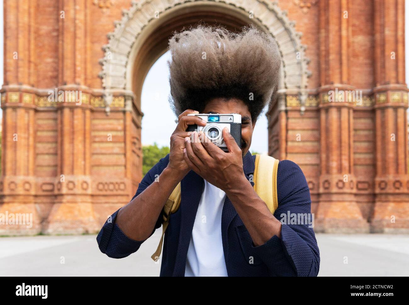 Schwarzer Mann, der ein Bild nimmt, während er mit der Kamera zugewandt ist  Eine Kamera im Triumphbogen von Barcelona Stockfotografie - Alamy