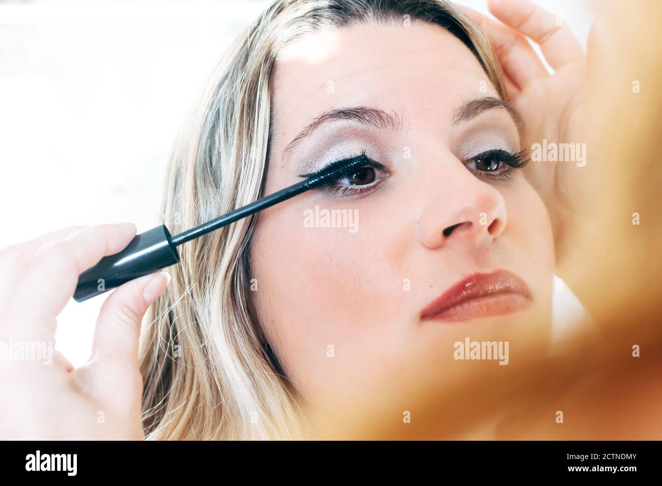 Nahaufnahme von unkenntlich Make-up Künstler Anwendung schwarze Mascara auf Wimpern Des weiblichen Modells im Schönheitssalon Stockfoto