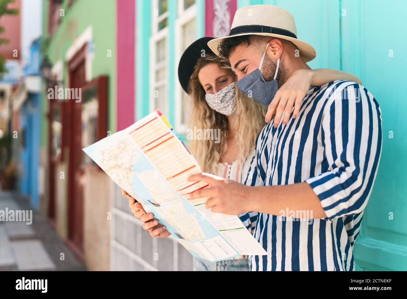 Junges Paar trägt Gesichtsmaske und hält Reisekarte - Reisende Menschen genießen erste Reise nach Corona-Virus Ausbruch Stockfoto Junges Paar trägt Gesichtsmaske und hält Reisekarte - Reisende Menschen genießen erste Reise nach Corona-Virus Ausbruch Stockfoto