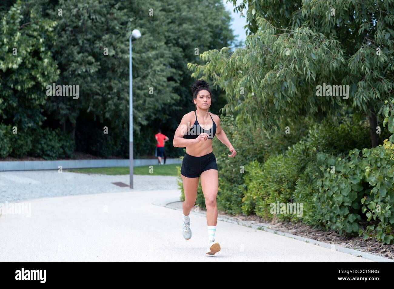 Fokussierte afroamerikanische Athletin in Sportbekleidung laufen entlang Weg Im städtischen Park während des Trainings im Sommer Stockfoto