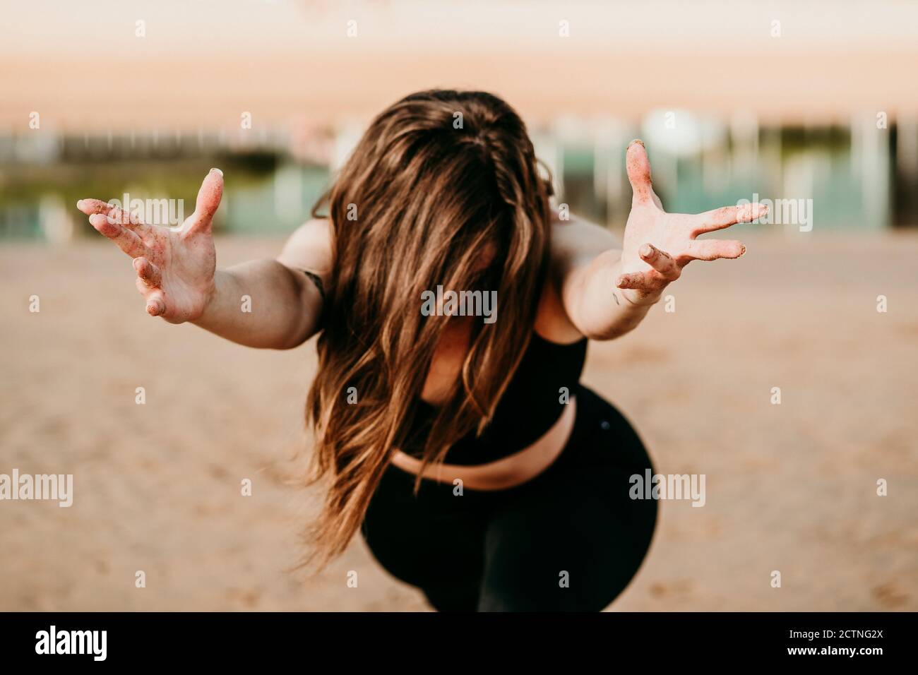 Nicht erkennbare Frau, die in Anjaneyasana steht und die Hände zur Kamera reicht Beim Yoga am Strand Stockfoto