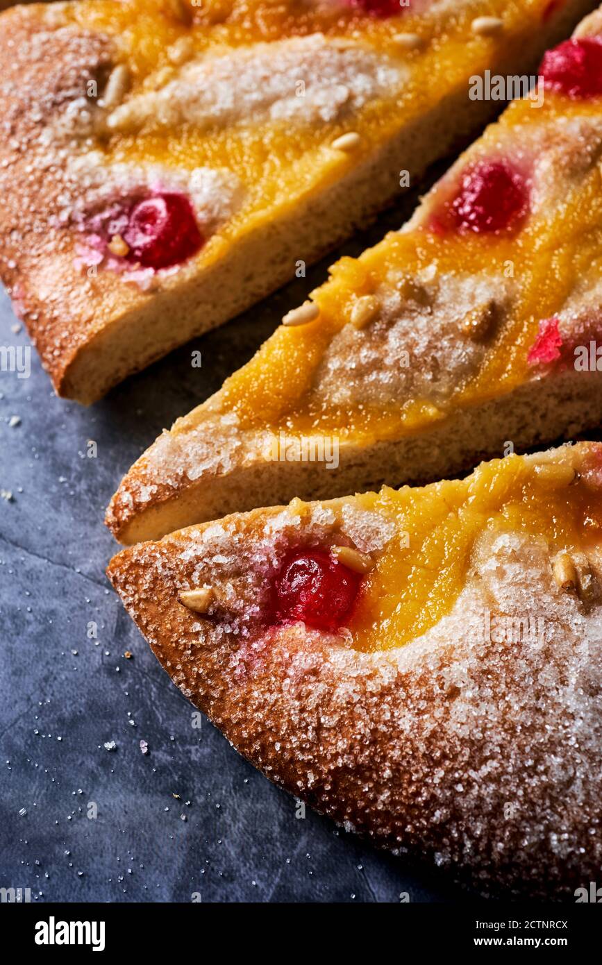 Nahaufnahme einiger Stücke einer Coca de Sant Joan, ein typischer süßer flacher Kuchen aus Katalonien, Spanien, gegessen an der St. Johns Eva, auf einer grauen Steinoberfläche Stockfoto