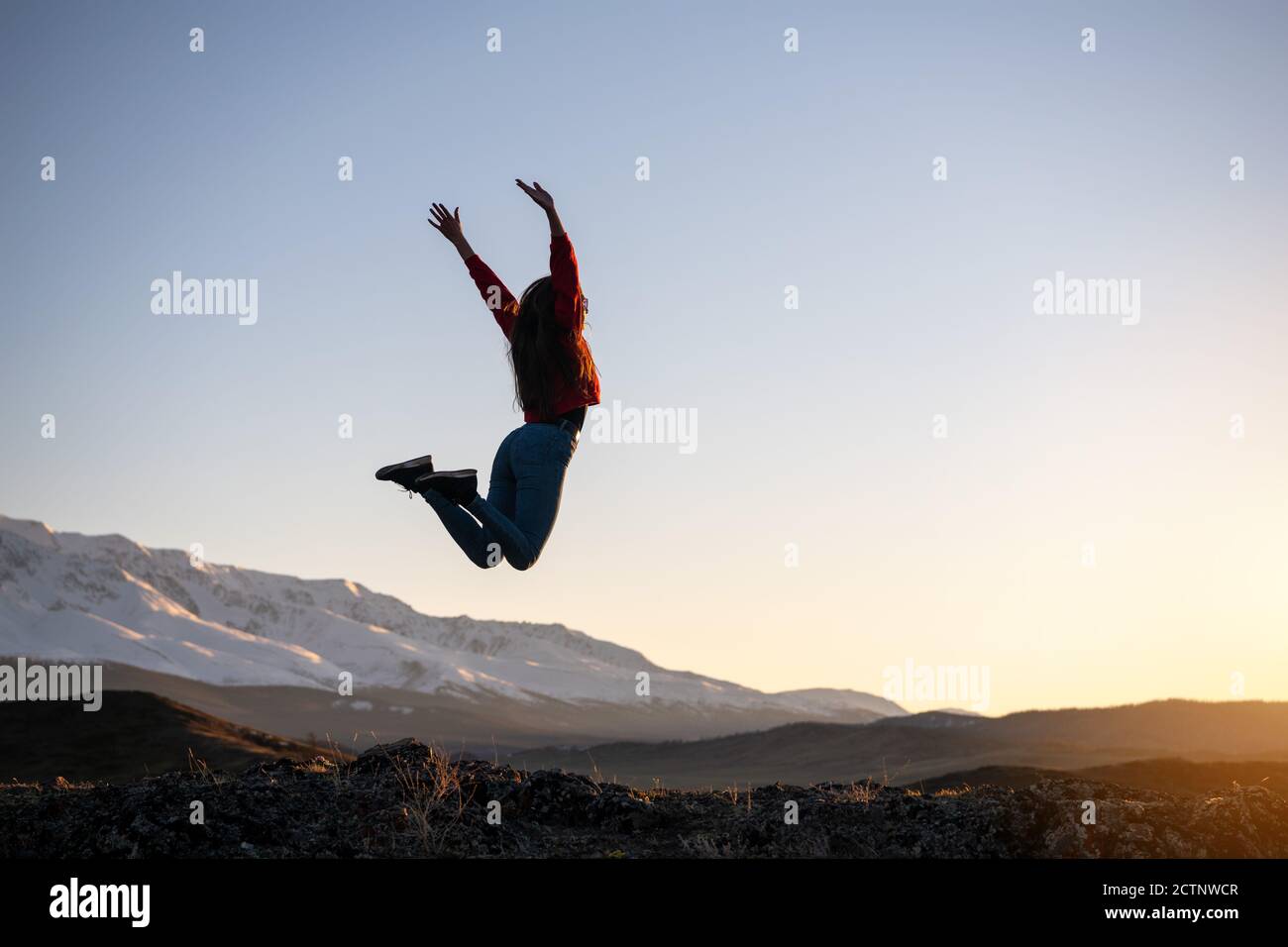 Schlank glücklich Mädchen springt gegen Berge und Sonnenuntergang. Reisekonzept Stockfoto