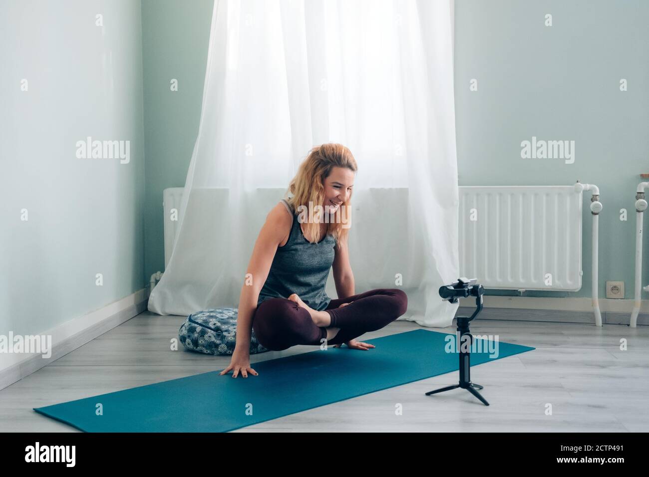 Weibliche Yoga-Lehrerin verbunden von zu Hause Blogging und vlogging Rundfunk Unterricht über soziale Medien mit Smartphone auf Gimbal Stockfoto