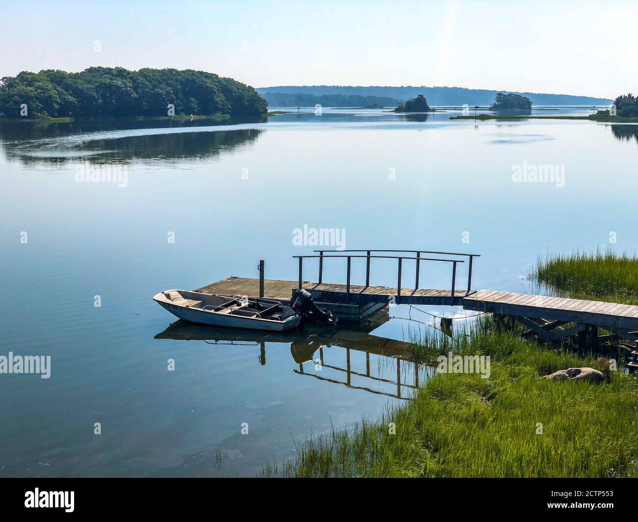 Kleines Motorboot wird an einem kleinen Dock an einem ruhigen Morgen auf dem Westport River, Westport, MA gebunden Stockfoto