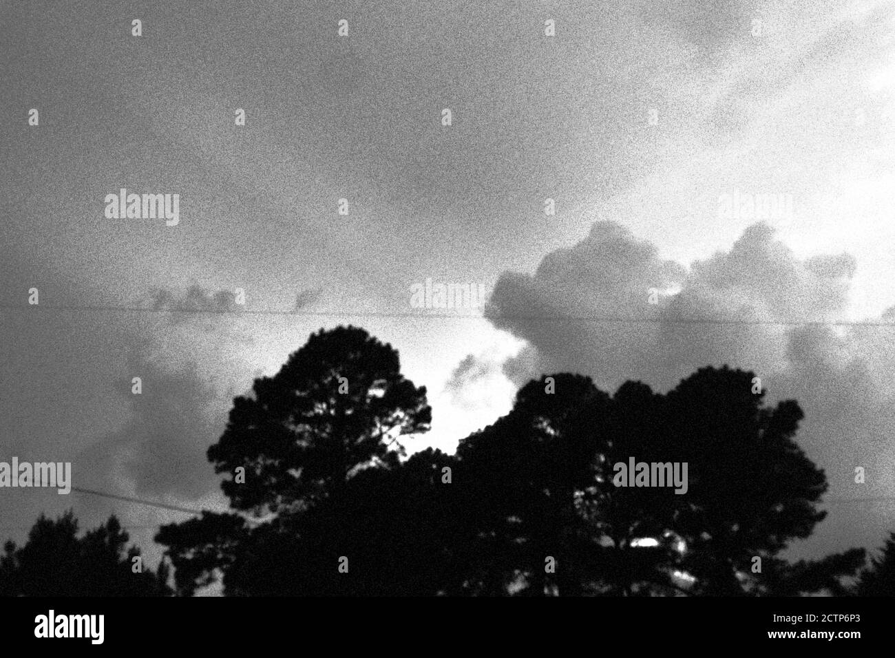 Schwarze und weiße Sonnenstrahlen hinter Wolken Stockfoto