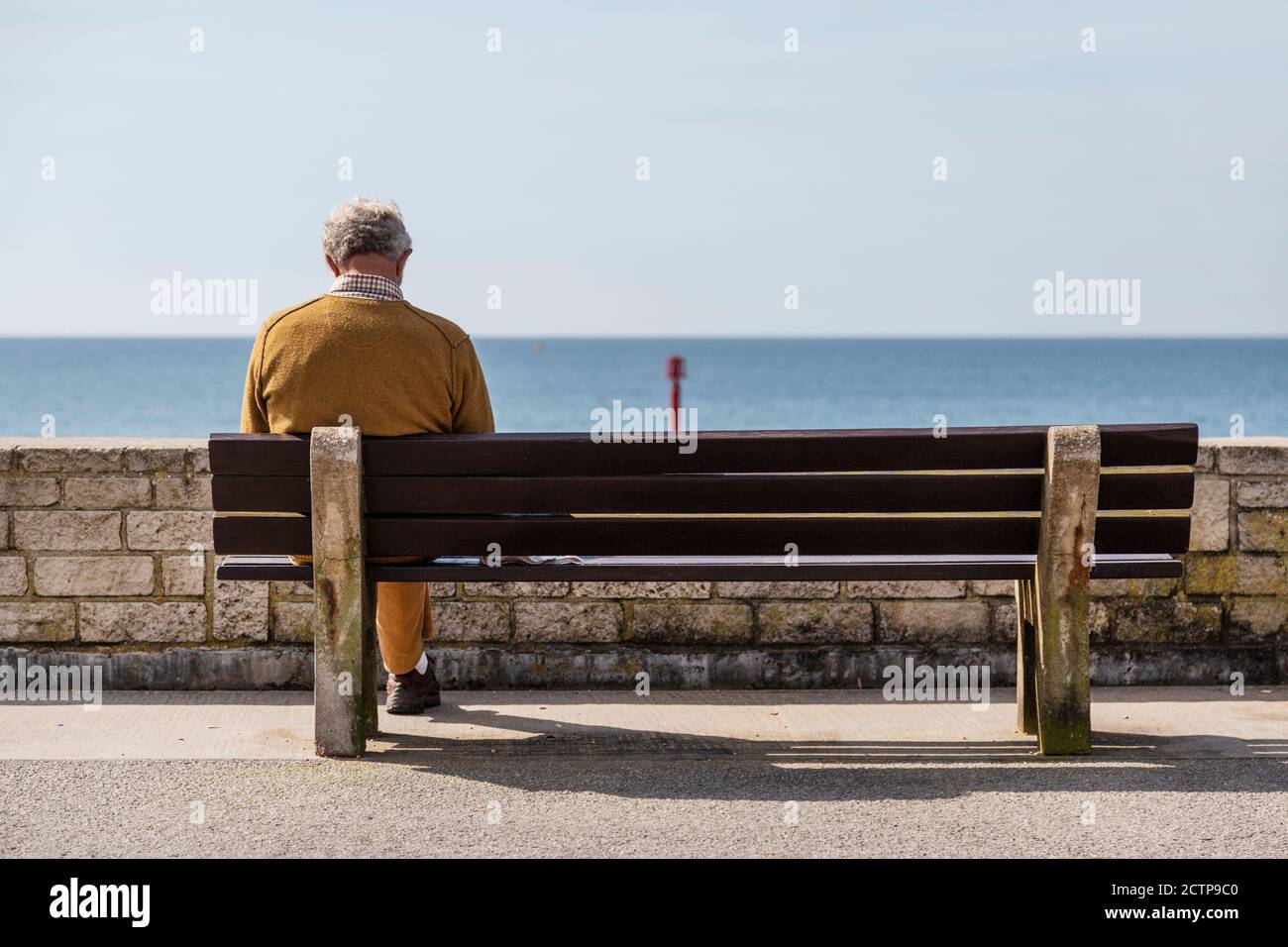 Mann saß auf einer Bank am Meer auf der Englische Küste Stockfoto