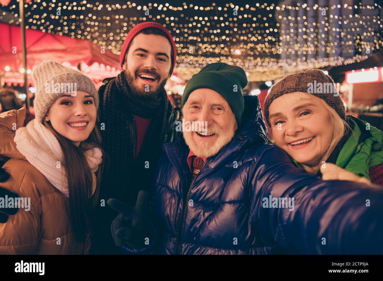 Nahaufnahme Porträt Foto der ganzen Familie vier Verwandte Menschen Weihnachten Treffen nehmen Selfie zeigen V-Zeichen Umarmung Oberbekleidung Hut Schal Mantel Zwei Generationen Abend Stockfoto
