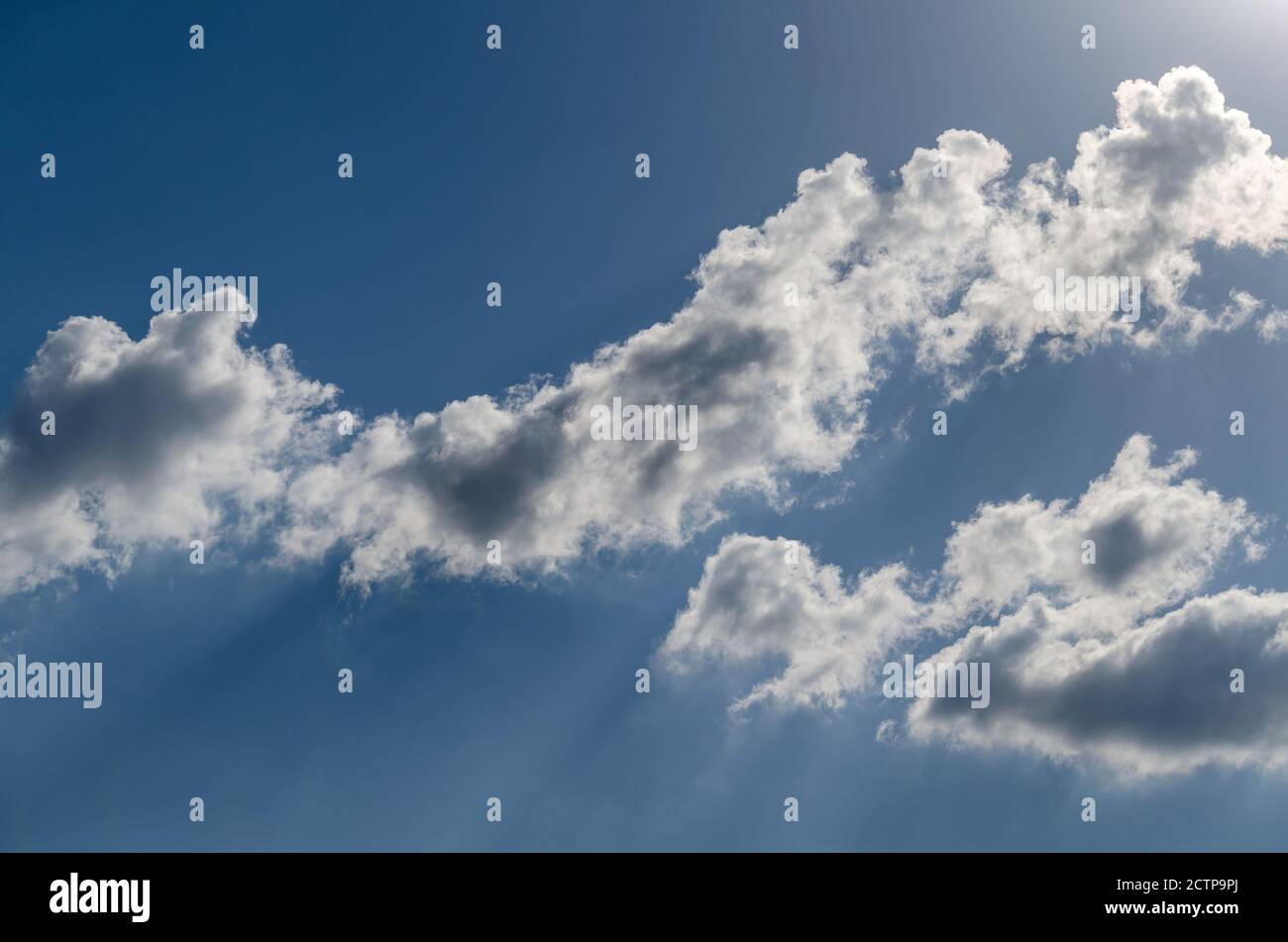 Flauschige Wolken in den Sonnenstrahlen am blauen Himmel Stockfoto