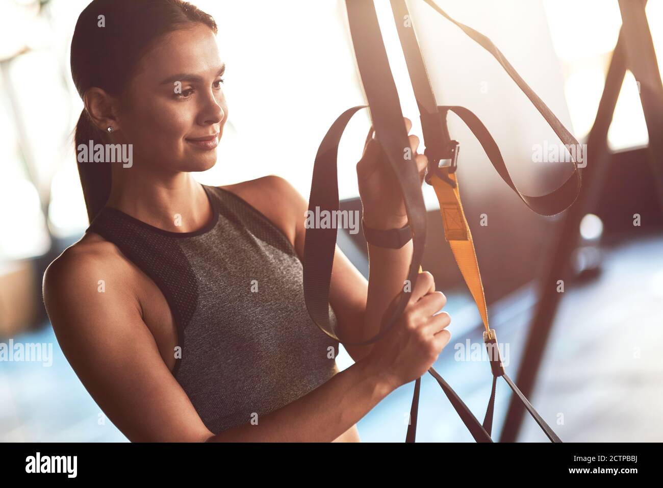 Junge schöne sportliche Frau, die beim Training im Fitnessstudio trx-Fitnessbänder anpasst. Sport, Training, Wellness und gesunder Lebensstil Stockfoto