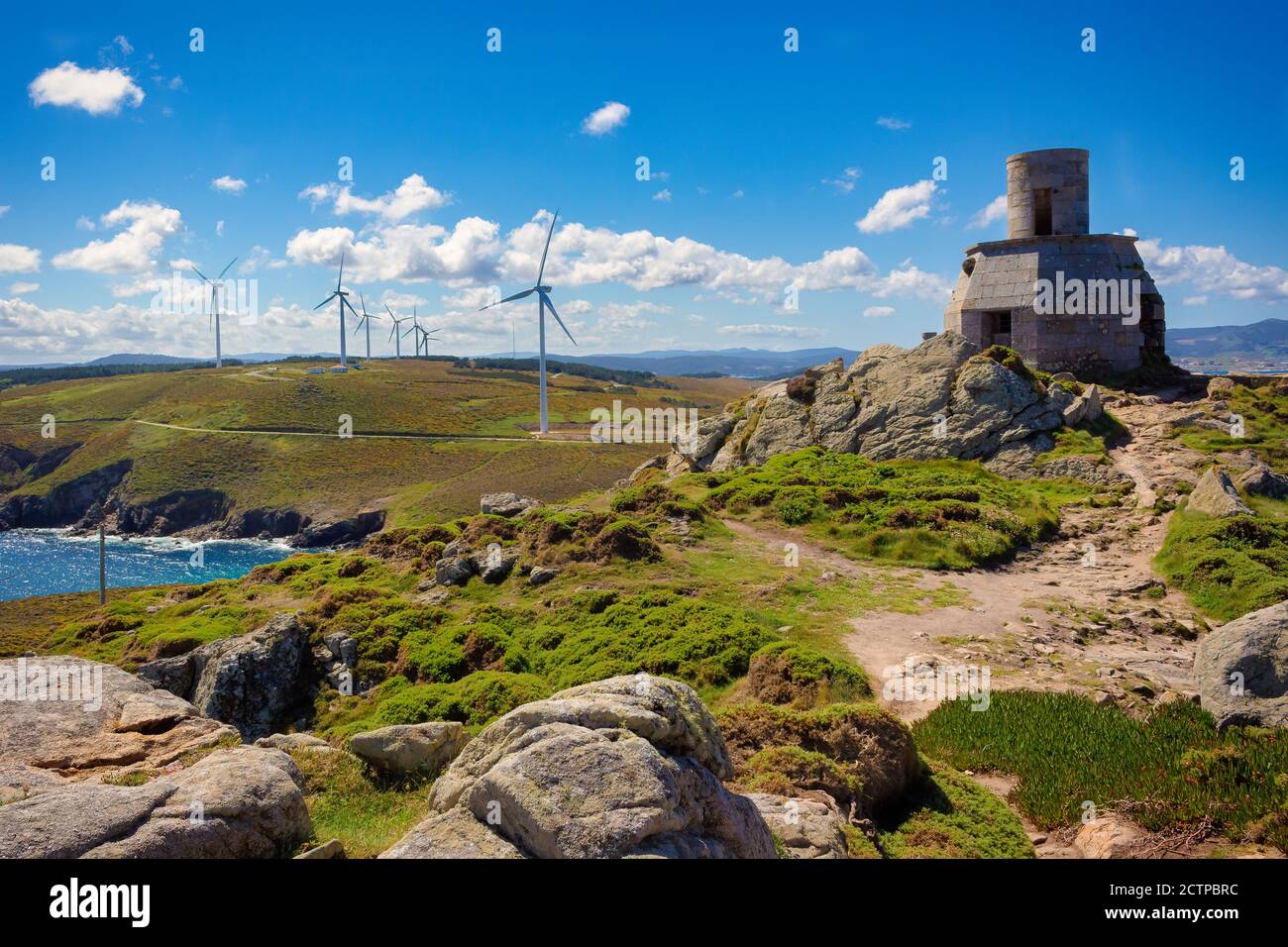 Blick auf die Ruinen des alten Leuchtturms von Vilán, mit Windmühlen im Hintergrund, Galizien, Spanien Stockfoto