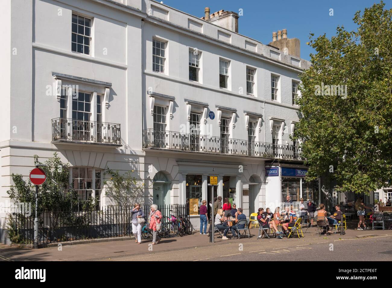 Menschen sitzen vor einem Café in der Sonne in der Plains in der historischen Marktstadt Totnes in der South Hams, Devon, Großbritannien Stockfoto