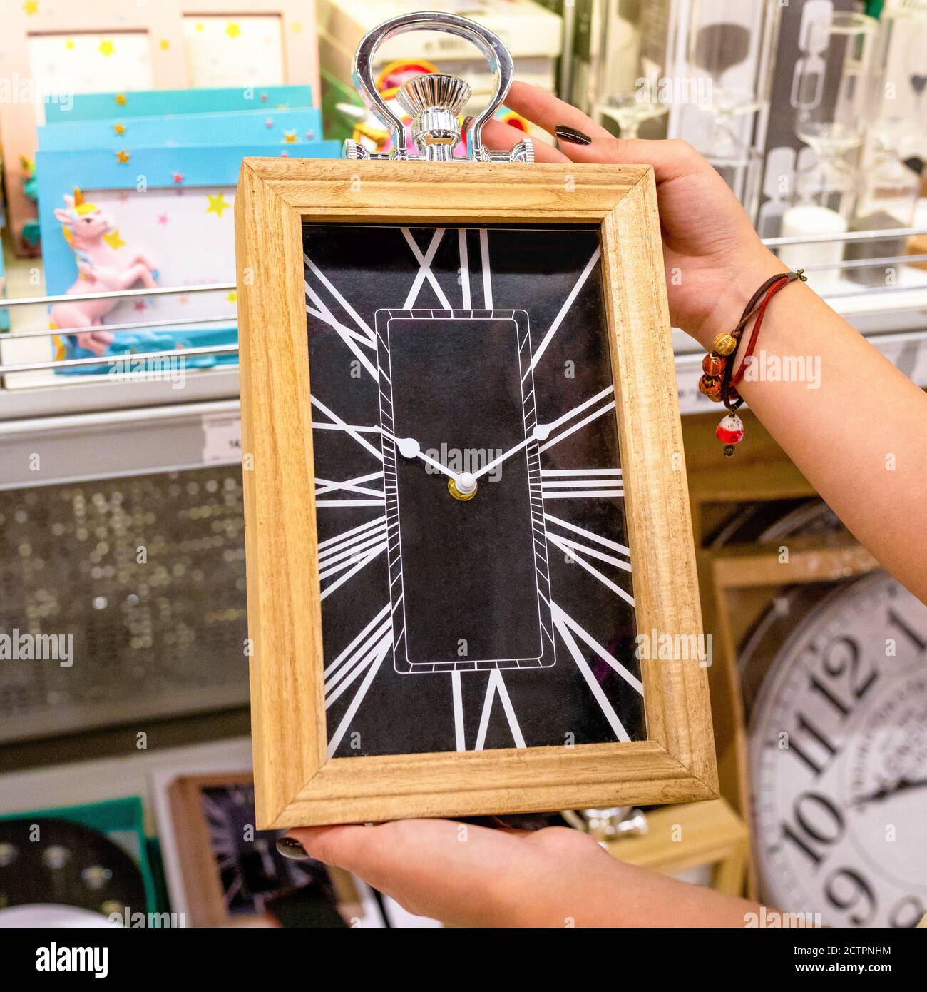Frau mit großer Wanduhr im Laden Stockfoto
