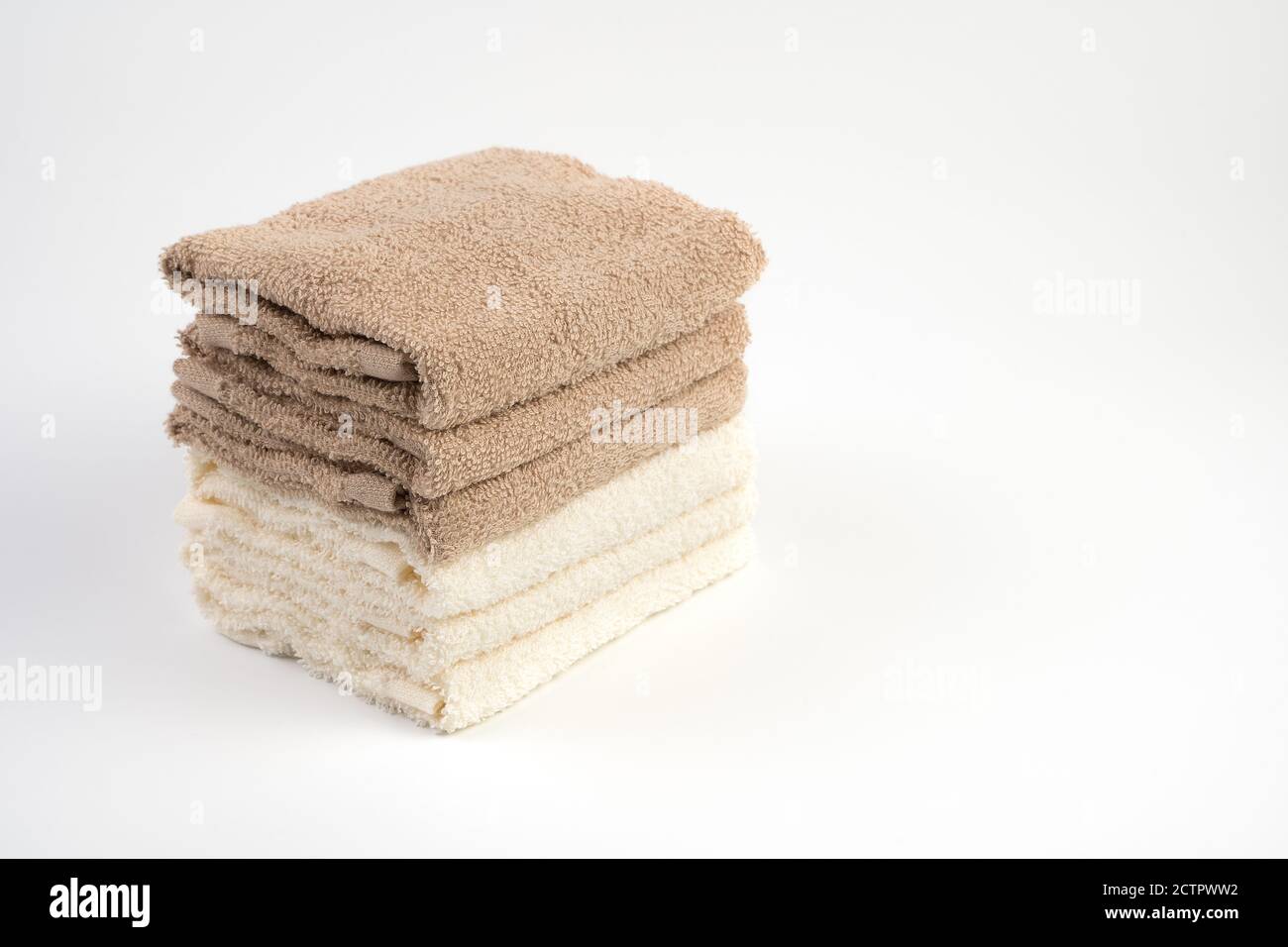 Ein Stapel Terry Handtücher weiß und hellbraun auf weißem Hintergrund. Stockfoto