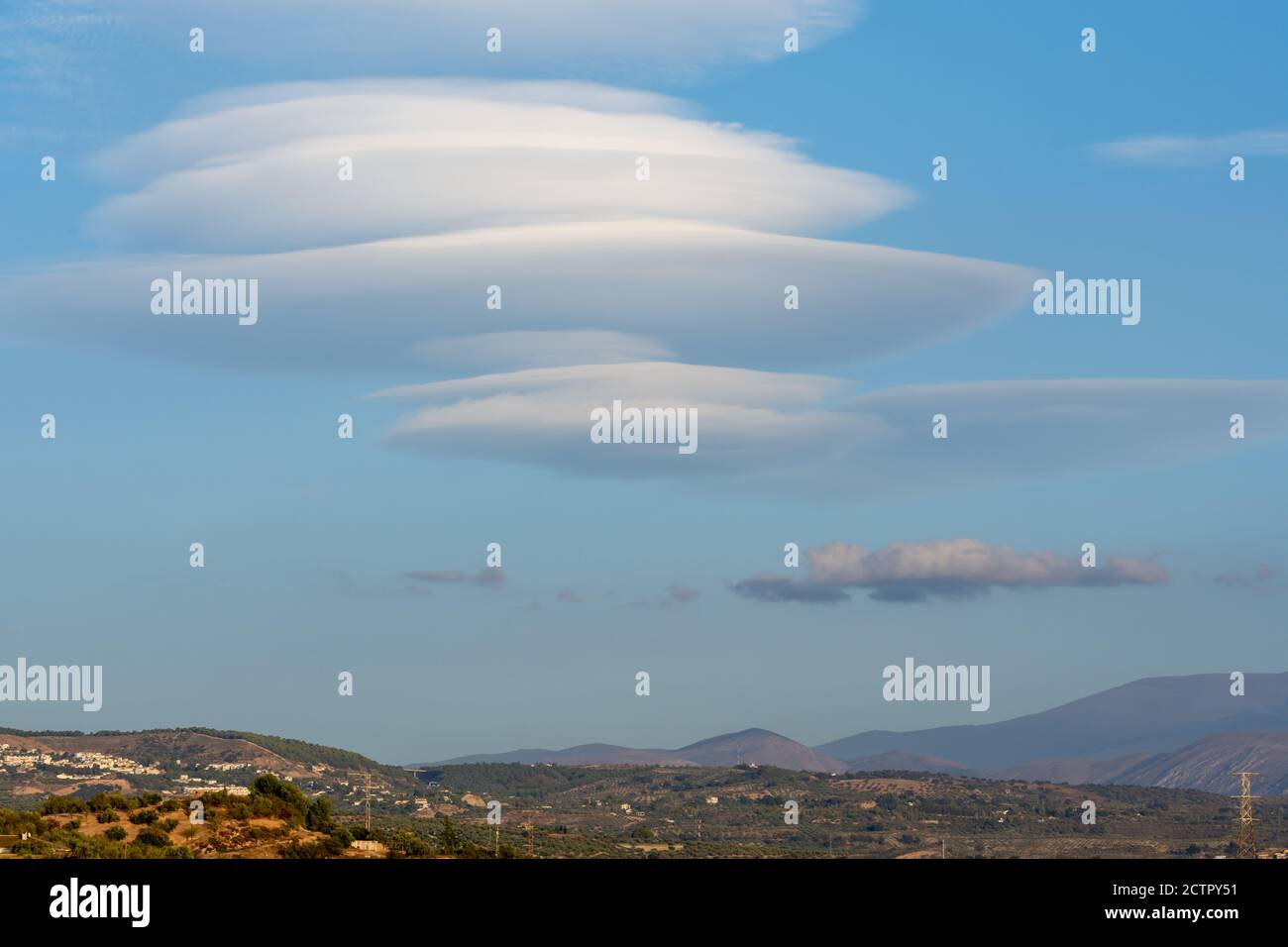 Weiße linsenförmige Wolken in blauem Himmel über Hügeln in Granada Stockfoto