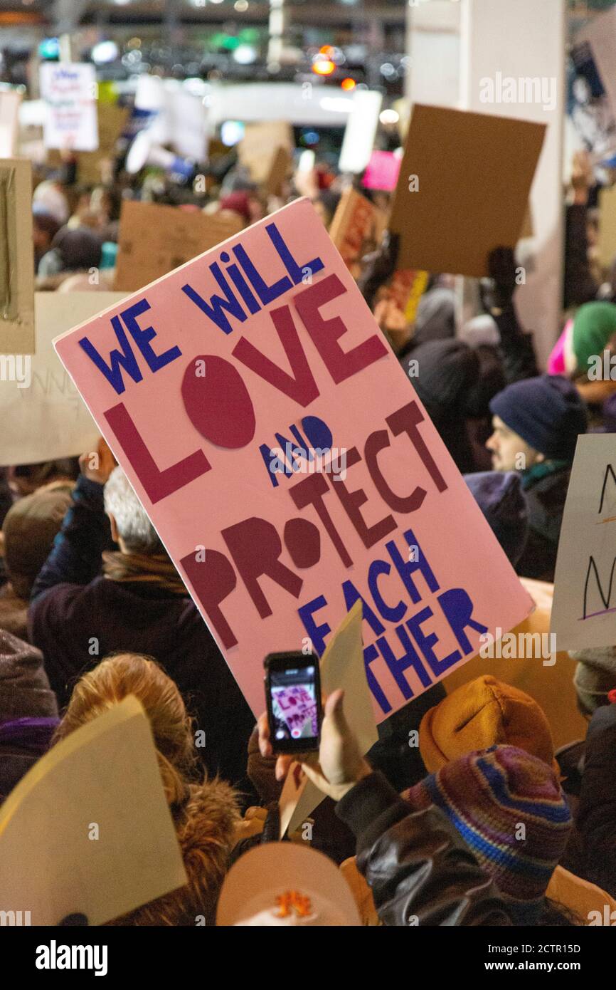 Protestler mit Schild "Wir werden einander lieben und schützen", Protest gegen muslimisches Reiseverbot, JFK Airport, New York, New York, USA Stockfoto