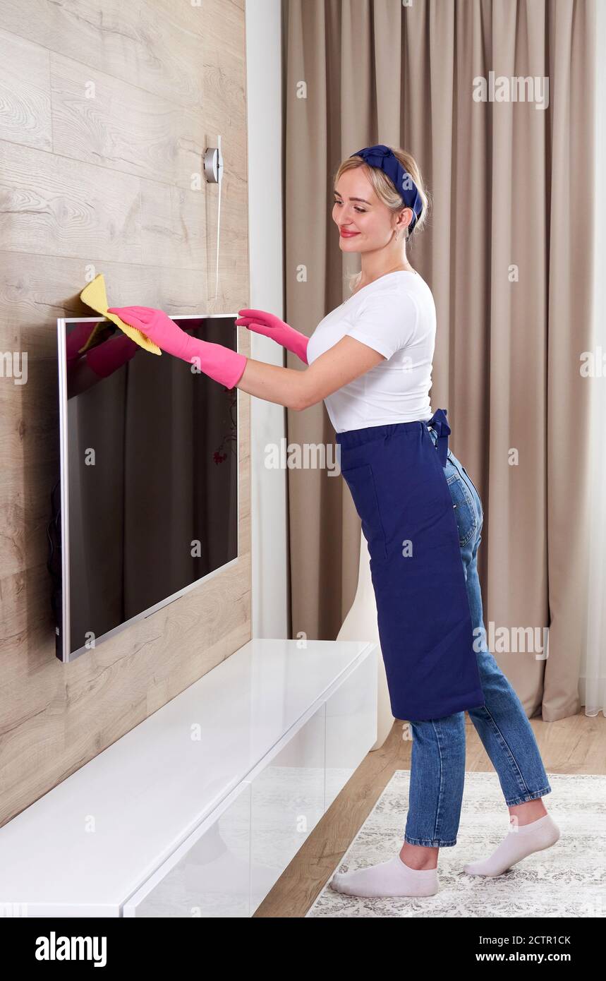 Schöne junge lächelnde Frau Putzhaus mit Mikrofaser Tuch. Frau Reinigung TV mit Reinigungsmittel zu Hause, Nahaufnahme. Junge Glückliche Frau Reinigung Der Stockfoto