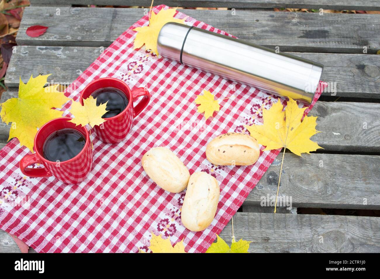 Gesundes Frühstück im Freien, rote Tassen und Thermoskannen, Herbststimmung Hintergrund Stockfoto