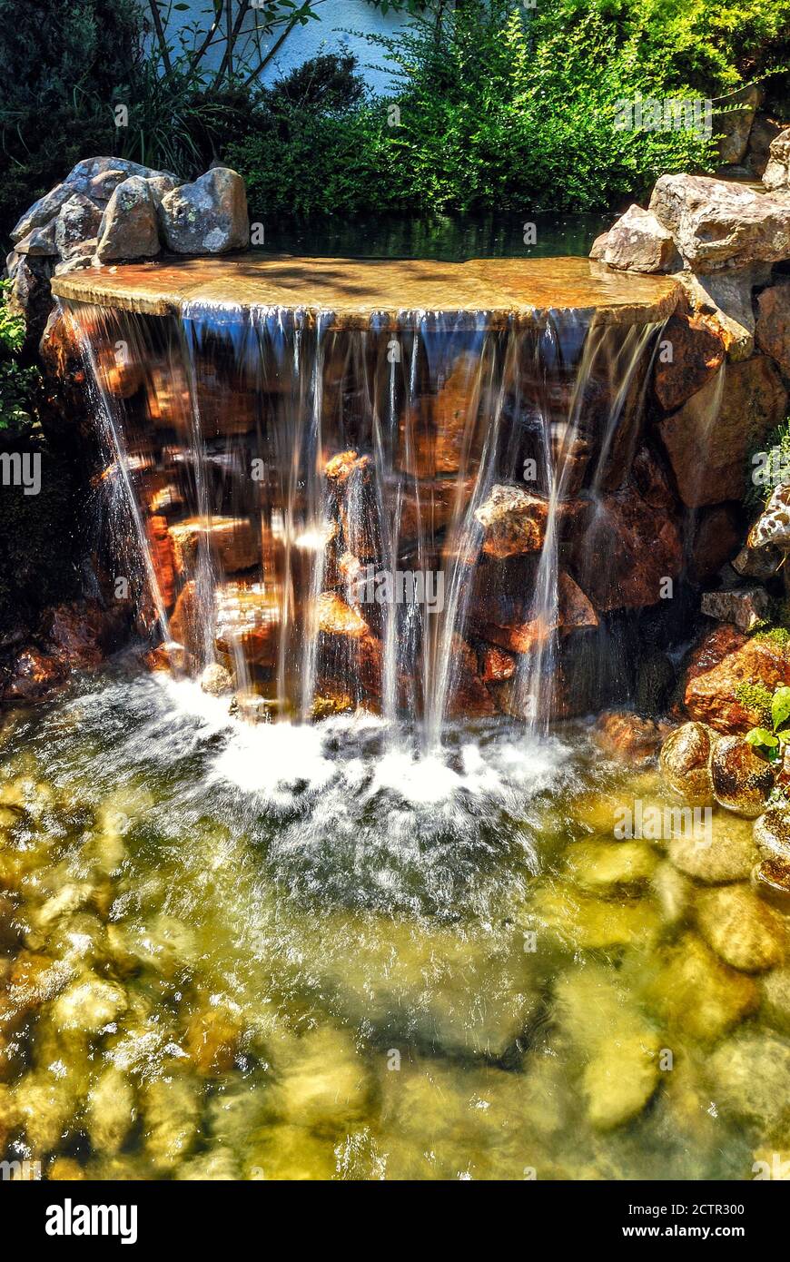 Kleiner künstlicher Wasserfall im künstlichen tropischen Garten Stockfoto
