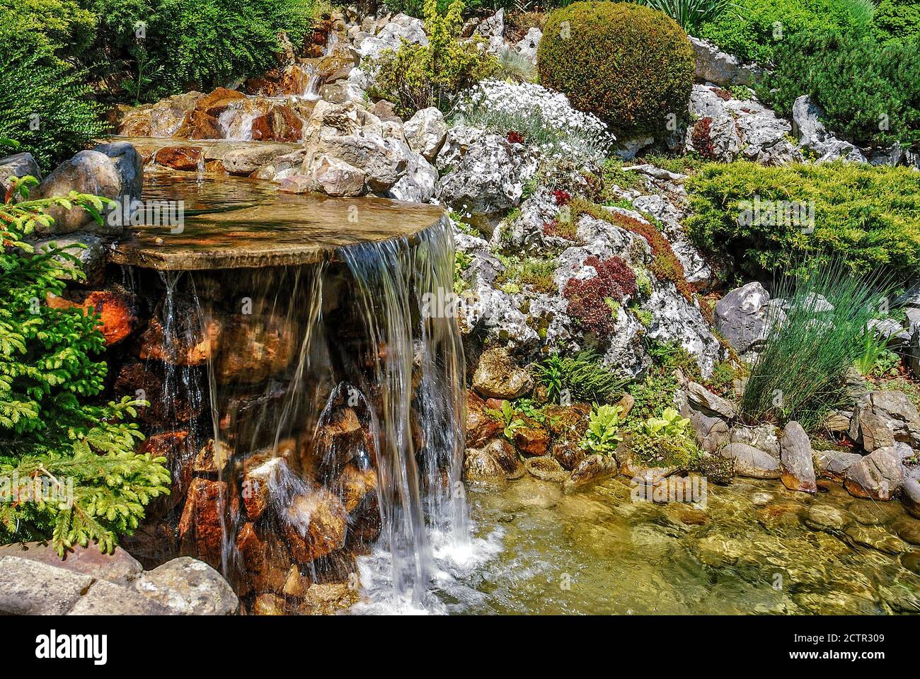Kleiner künstlicher Wasserfall im künstlichen tropischen Garten Stockfoto