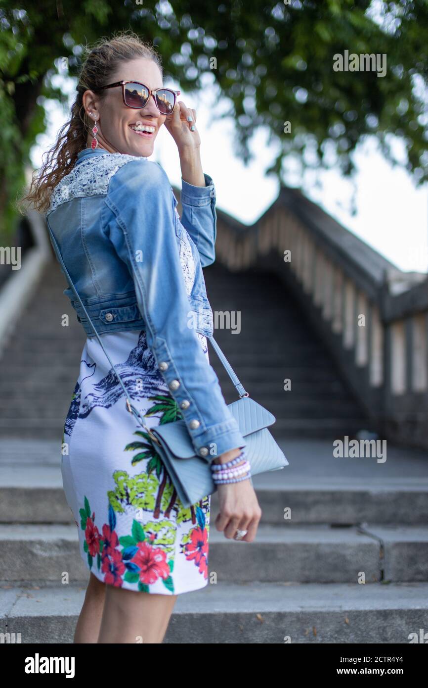 Junge 30s kaukasischen städtischen Frau hält Sonnenbrille im Park an Treppen Stockfoto