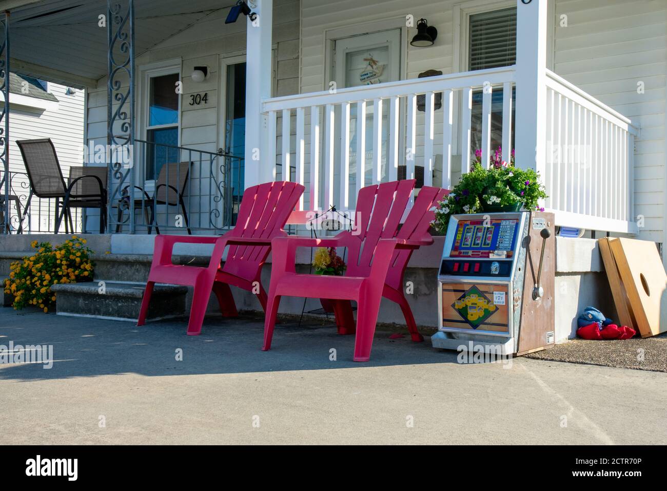 Die Vorderseite eines Strandhauses mit zwei Red Lawn Stühle und ein Spielautomat neben ihnen Stockfoto