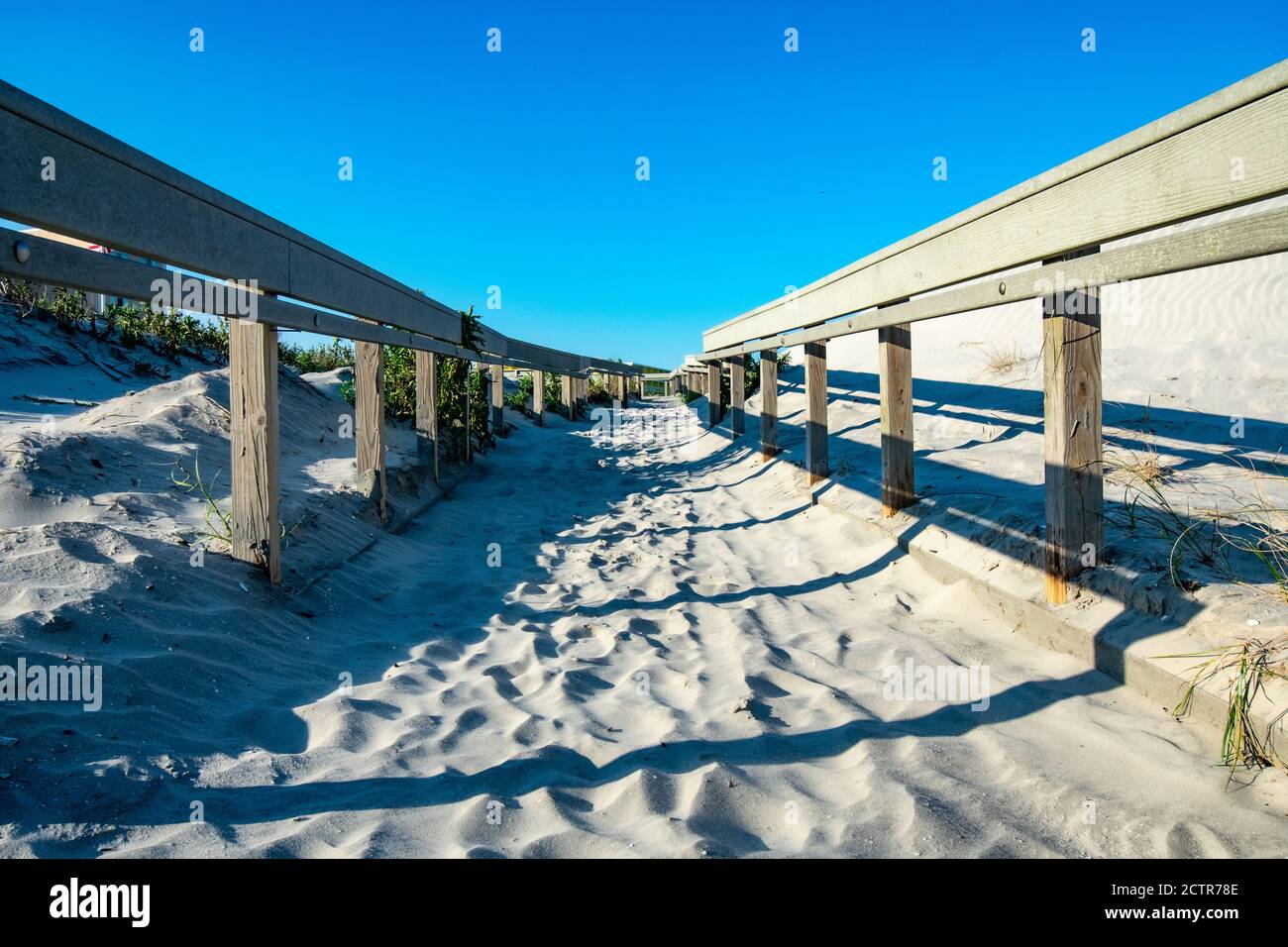 Ein Sandy Beach Path mit einem Holzzaun auf jedem Side Casting Shadows in Wildwood New Jersey Stockfoto