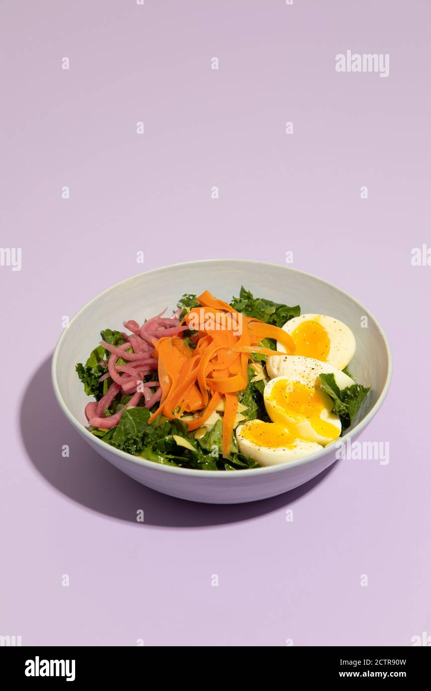 Eingelegte Karotten und Ei Salat gegen lila Hintergrund Stockfoto