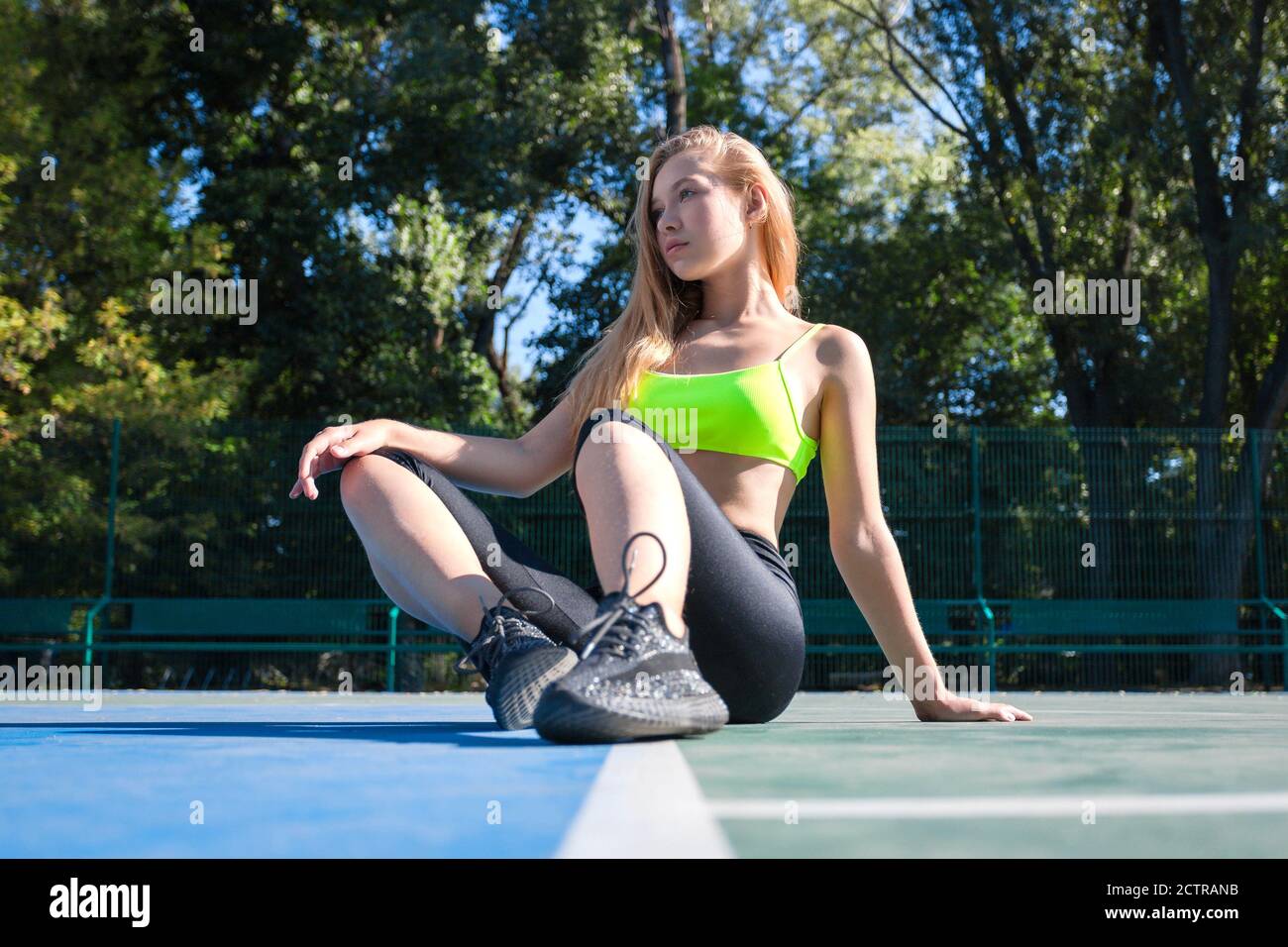 Sportliche junge Mädchen Modell sitzt auf Sportplatz bei sonnig Tag Stockfoto