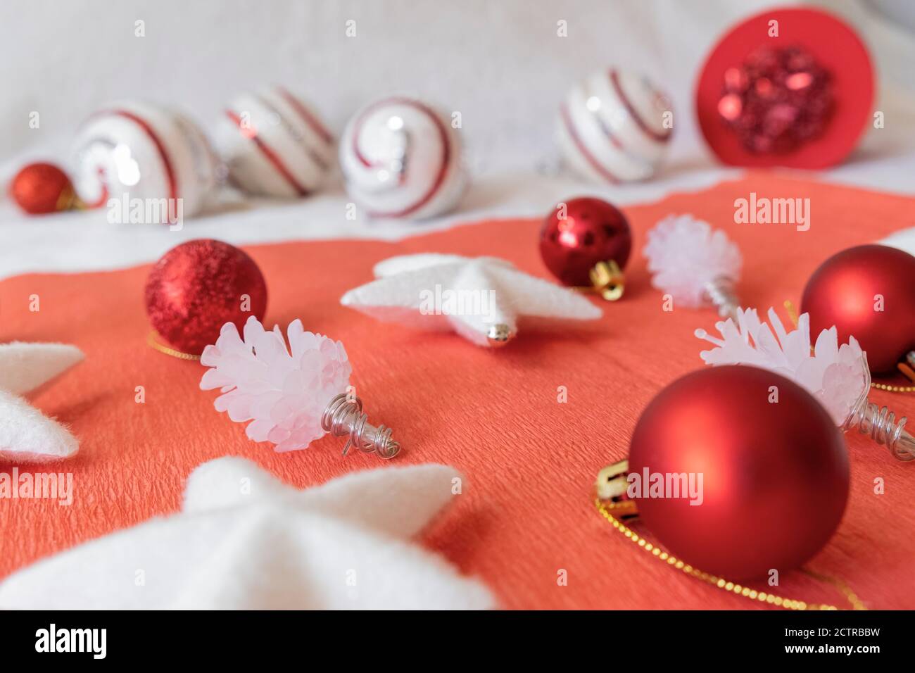 Weihnachtliche Gestaltung. Blick auf Weihnachtsdekorationen, vor rotem Hintergrund. Sterne, Unebenheiten und Bälle. Stockfoto